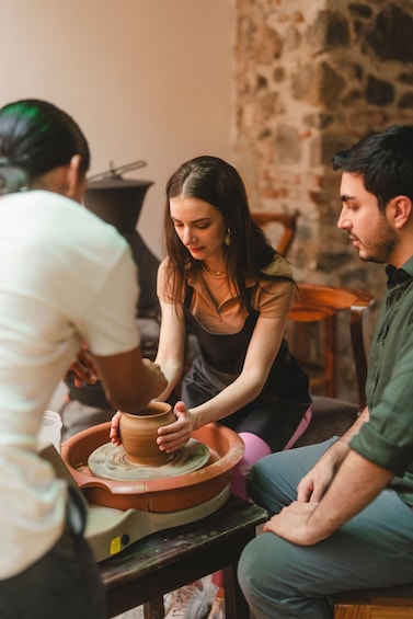 A person shaping a clay pot on a pottery wheel. 1