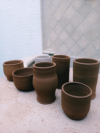Several brown ceramic pots of varying sizes on a speckled surface. 4