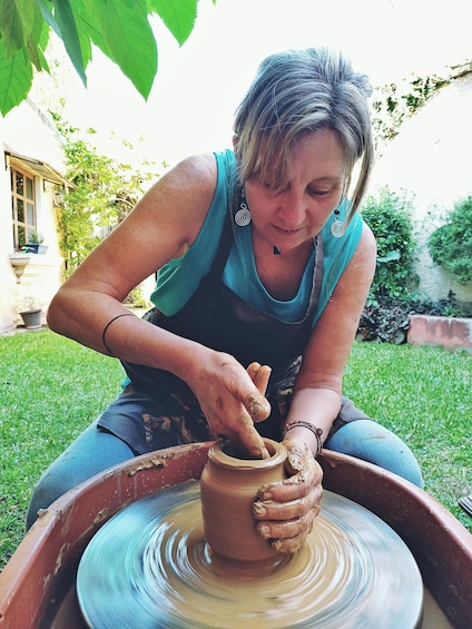 A person engaged in pottery making outdoors. 5