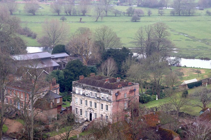 A large estate with a prominent central building, surrounded by trees and a body of water. 5