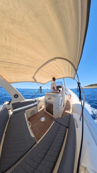 A sailboat with a person at the helm, a clear blue sea, and a distant shoreline. 5