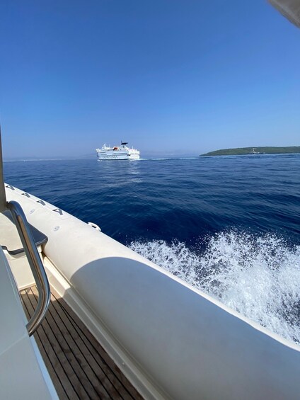 A boat named 'ADROLINTIA' on the water with a wake behind it. 1