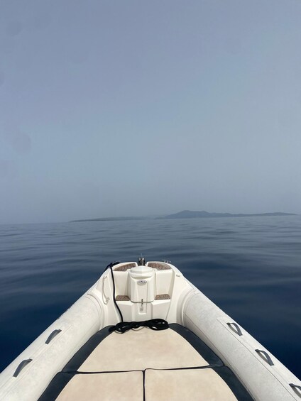 A boat on calm water with a clear sky and distant land. 4