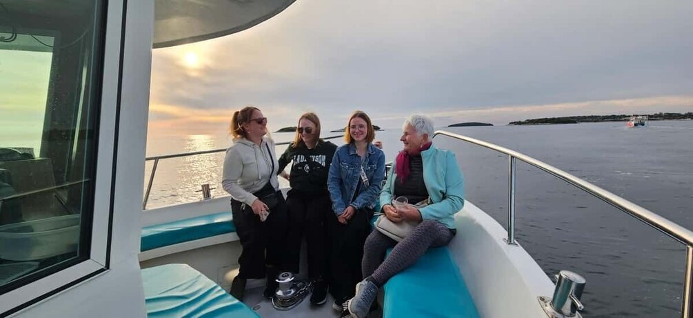 A group of people on a boat with a sunset in the background. 4