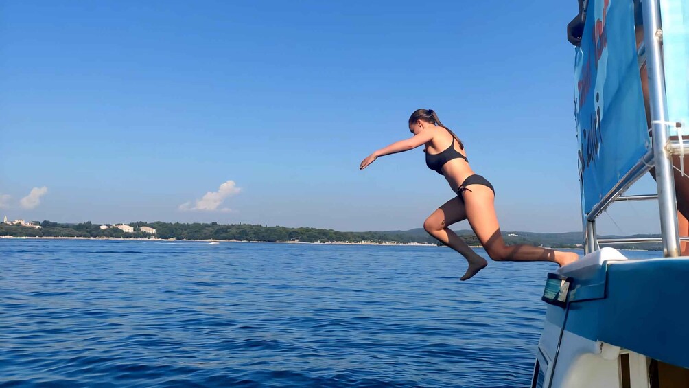 A woman in a bikini leaping from a boat into the sea. 1