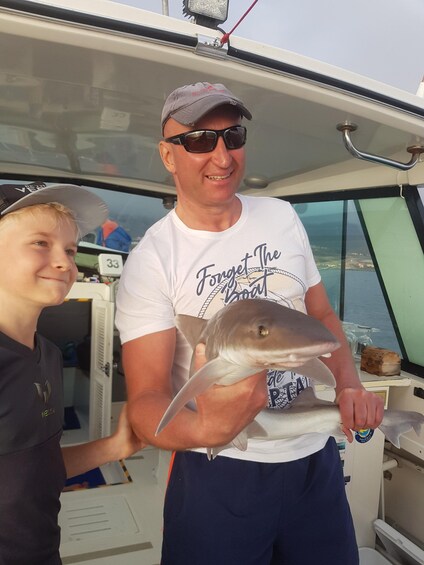 A person holding a fish on a boat. 1