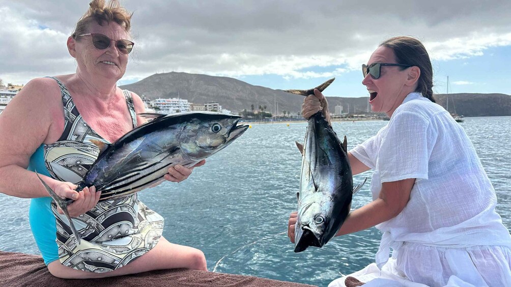 Two people holding fish on a boat with a mountainous landscape in the background. 3