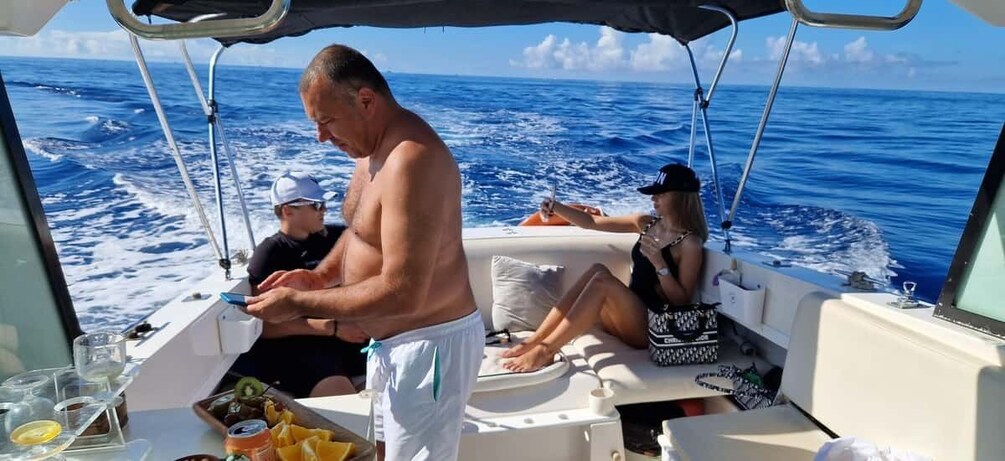A man standing on a boat, a woman sitting, and a child on the deck. 4