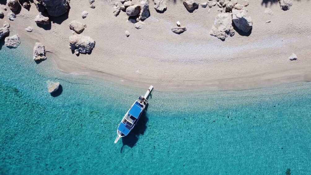 Un barco anclado cerca de una costa rocosa con agua turquesa cristalina. 1