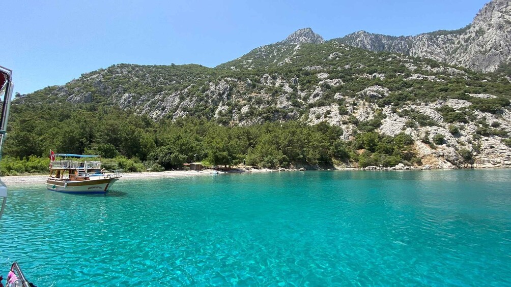 Un barco en un mar turquesa con montañas al fondo. 2