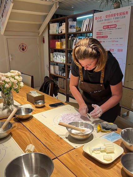 A person preparing food at a wooden table with various kitchen utensils and ingredients. 3