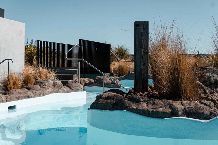 A swimming pool with a modern design, surrounded by rocks and dry grass. 2