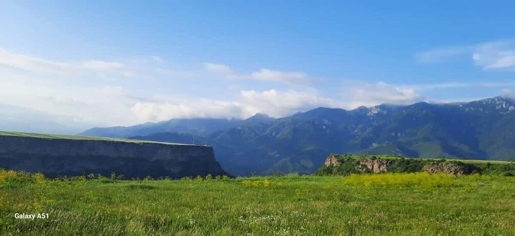 A grassy field with mountains in the background. 2