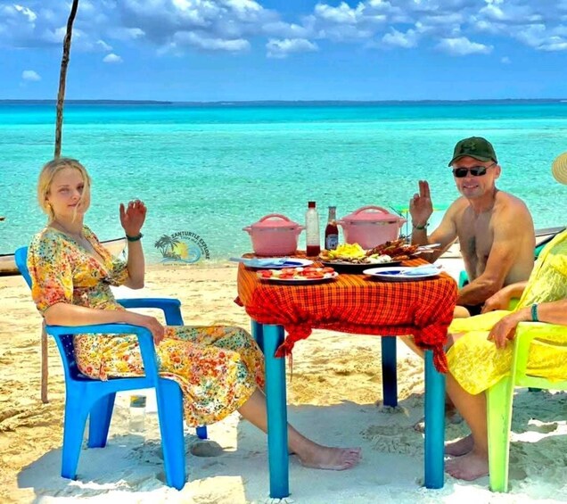A beach scene with a table set for two people, a clear blue sky, and turquoise water. 1