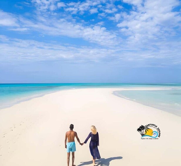 A couple holding hands on a white sandy beach with clear blue water and a clear sky. 5