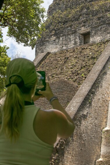 A person taking a photo of a large stone structure with a narrow opening. 4