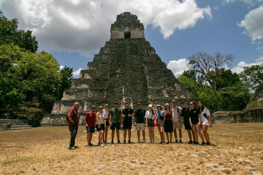 A group of people standing in front of a large pyramid-like structure. 1