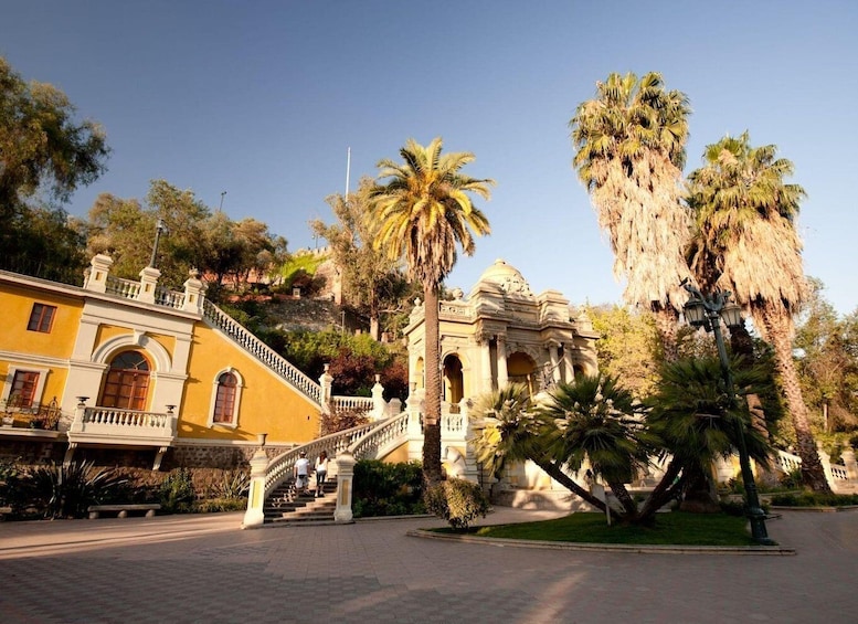 A yellow building with a staircase, palm trees, and a clear blue sky. 3