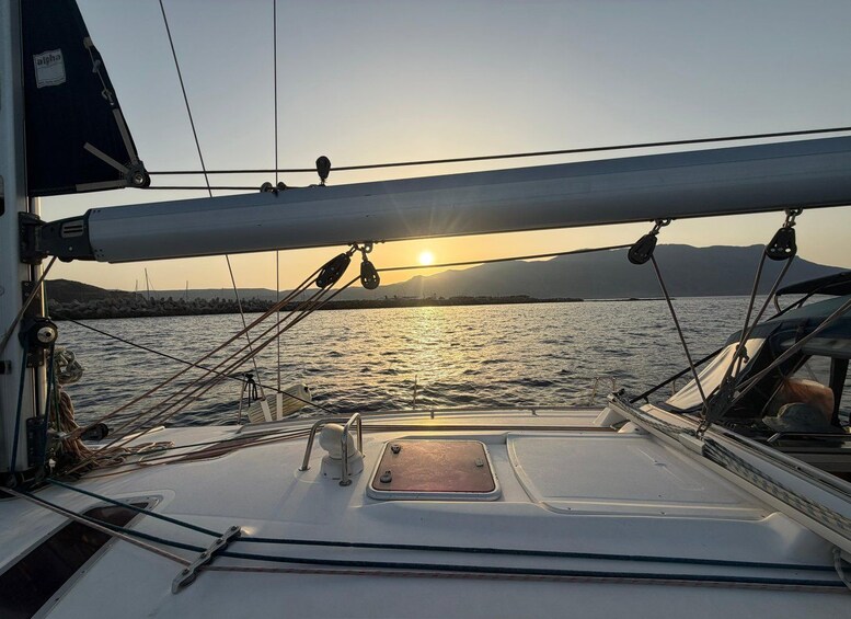 A sailboat at sunset with a calm sea and distant mountains. 2