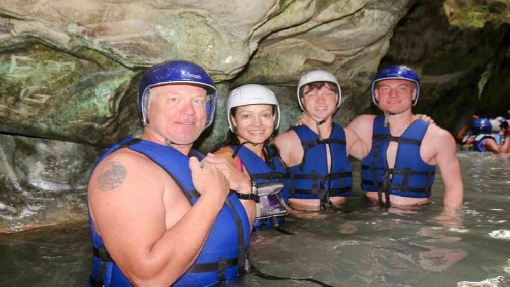 A group of people in a cave with water, wearing helmets and life vests. 4