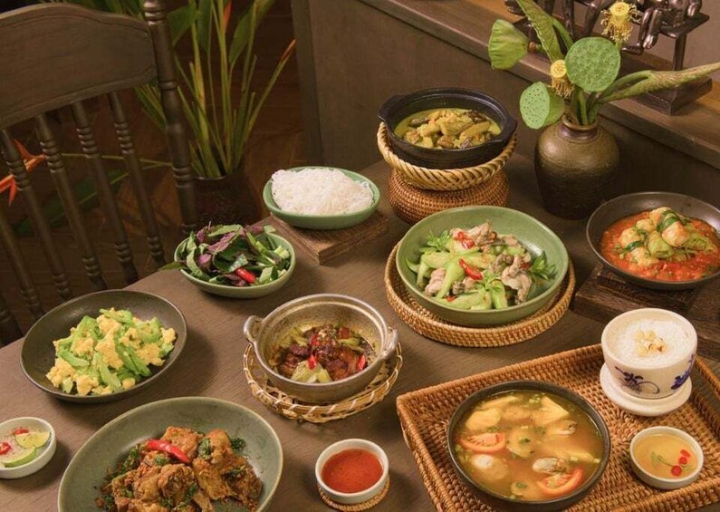 A variety of dishes on a wooden table, including bowls of soup, rice, and salads. 2