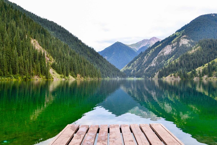 A calm lake surrounded by forested mountains. 2