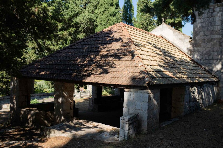 A stone structure with a tiled roof, surrounded by trees. 4