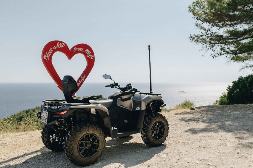 A quad bike parked on a dirt path with a heart-shaped sign that reads 'Blow a kiss from Mijeti.' 1