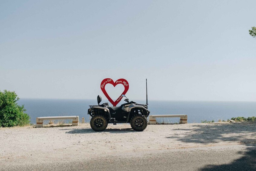 An ATV parked on a gravel path with a heart-shaped sign in the background. 3