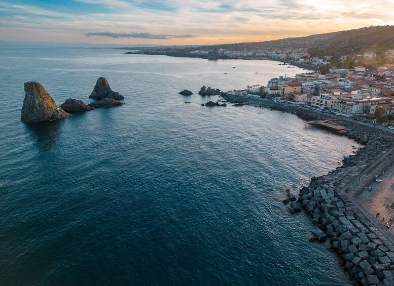 A coastal town with rocky outcrops and a stone breakwater. 1