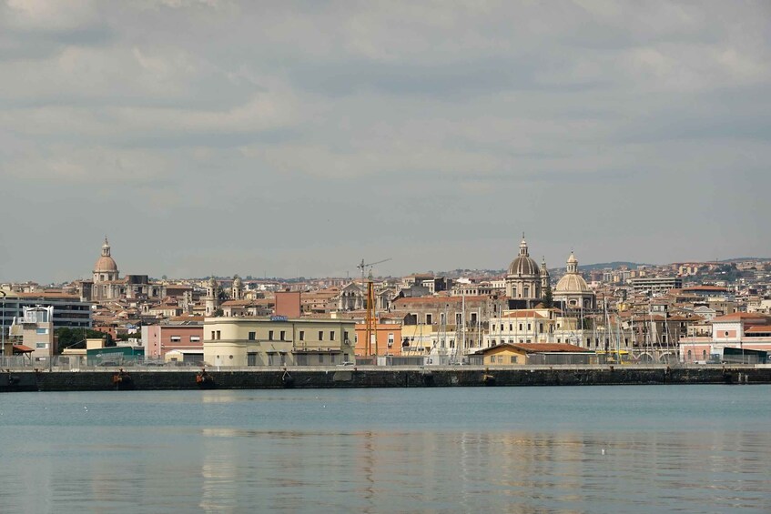 A coastal cityscape with historic buildings, a prominent dome, and a calm waterfront. 4