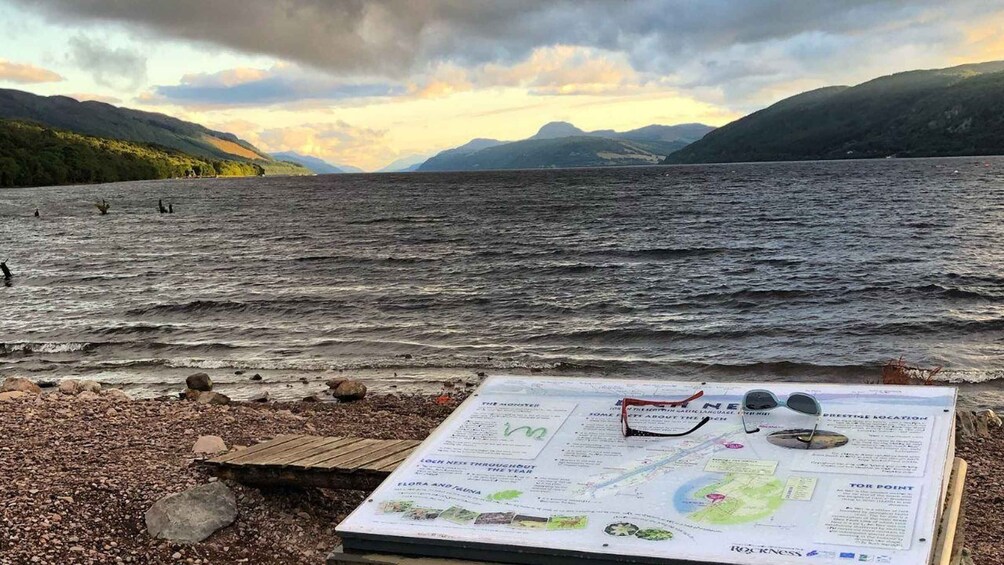 A rocky shoreline with a map and binoculars on a wooden stand. 4