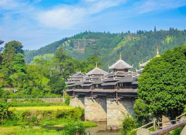 A traditional temple complex with tiered roofs and a stone wall, surrounded by lush greenery and terraced fields. 2