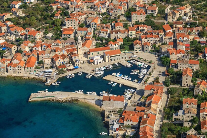 An aerial view of a coastal town with historic buildings, a marina, and a clear blue harbor. 3
