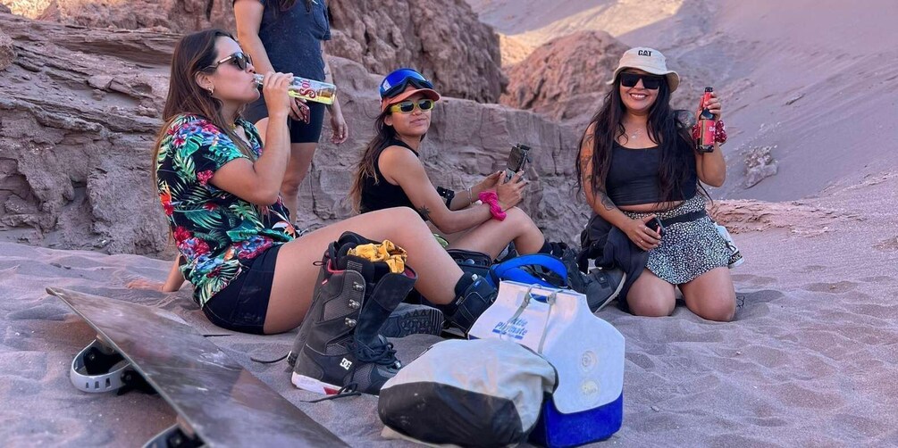 Three people sitting on a rocky surface with backpacks and a skateboard, in a mountainous area. 4