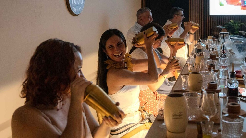 A group of people toasting with golden goblets at a table with various glasses and bottles. 1