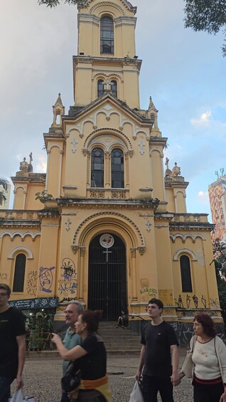 A yellow church with a bell tower, arched windows, and a large black door. 2