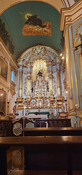 An ornate church interior with a large altar, golden decorations, and a mural on the ceiling. 5