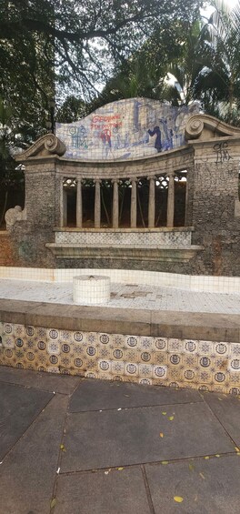 A stone monument with columns and a tiled roof, surrounded by trees. 4