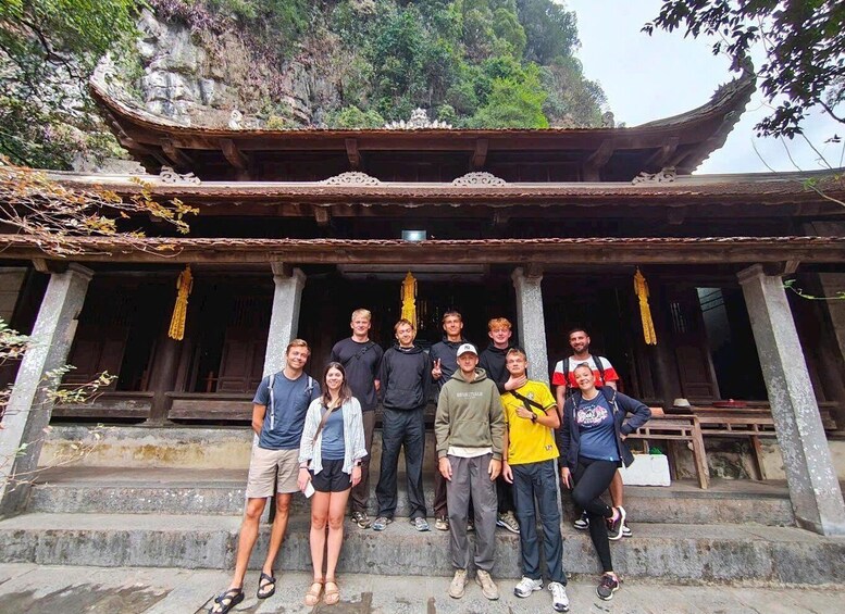 A group of people standing in front of a traditional building with a steep roof and stone columns. 2