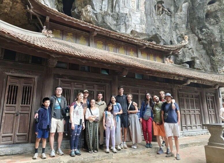 A group of people standing in front of a traditional building with ornate wooden doors and a tiled roof. 1