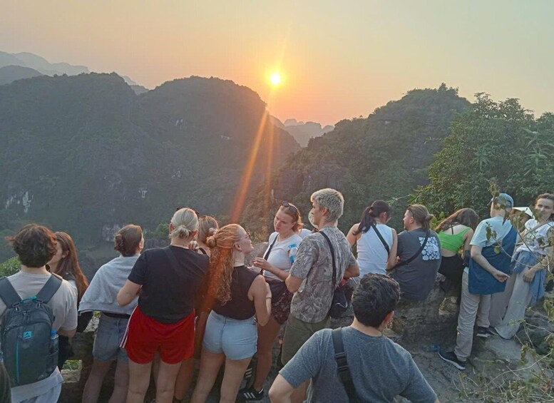 A group of people standing on a mountain overlooking a sunset. 5