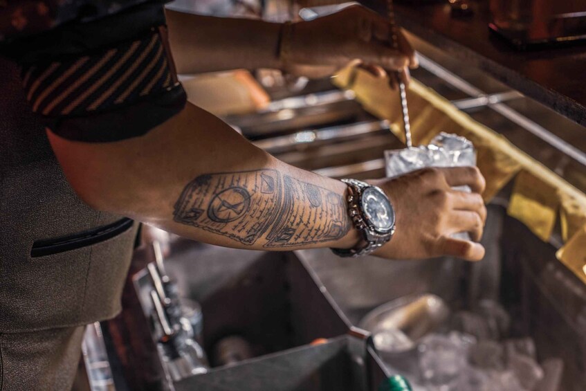 A person with a tattoo on their arm holding a drink. 4