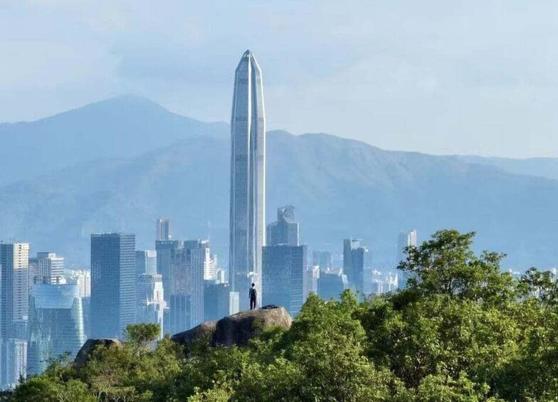 A cityscape with a prominent skyscraper, lush greenery, and distant mountains. 4
