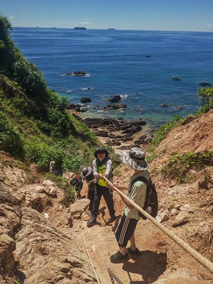 Hikers on a rocky trail with the ocean in the background. 2