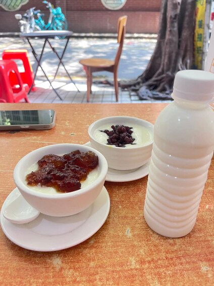 A table with a dessert bowl, a bottle, and a phone. 2