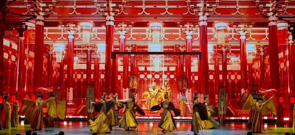 A stage with performers in traditional costumes, a red backdrop, and ornate architectural elements. 4