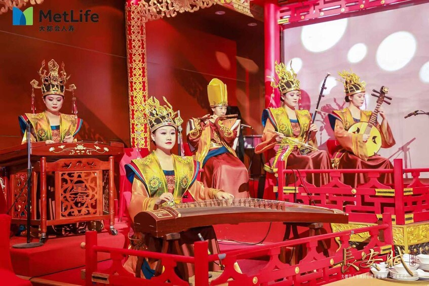 A traditional Chinese performance with musicians and a singer, set against a red backdrop with ornate decorations. 3