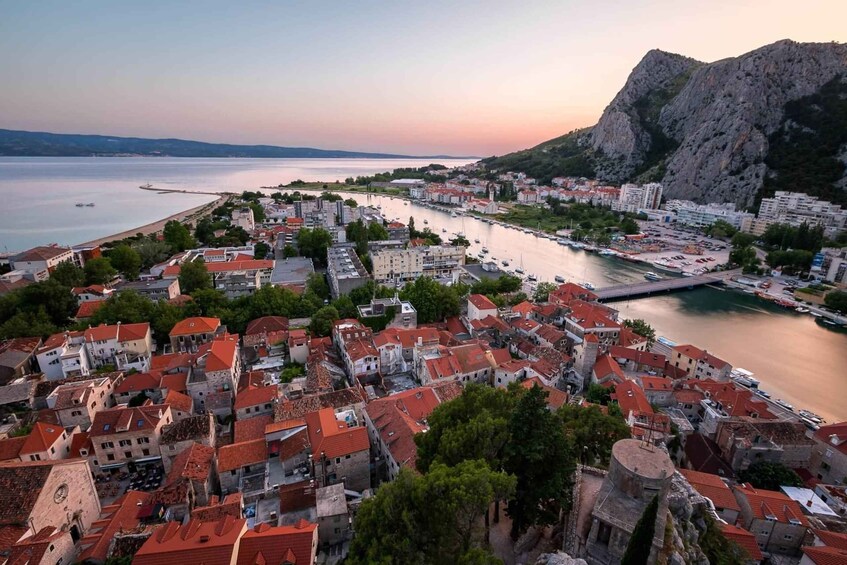 A coastal town with red-roofed buildings, a marina, and a mountain in the background. 5