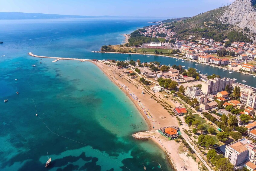 A coastal town with a beach, boats, and buildings. 1